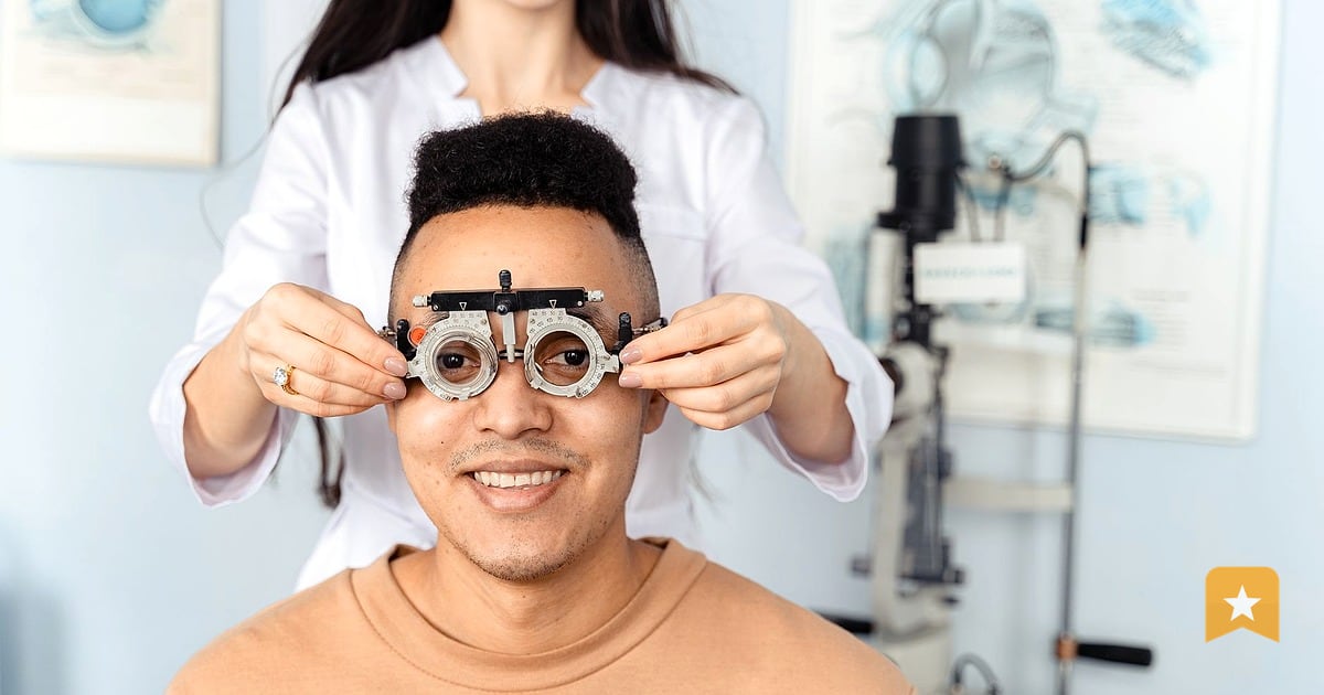 Optometrist adjusting trial frame on patient during eye exam in bright clinical room