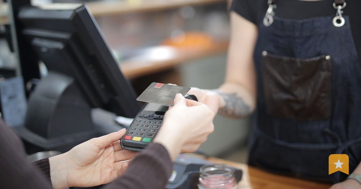 Customer handing a credit card to a small business owner at a wooden counter