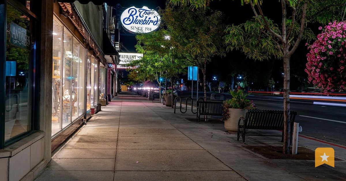 Storefront with lit neon sign on a quiet evening street