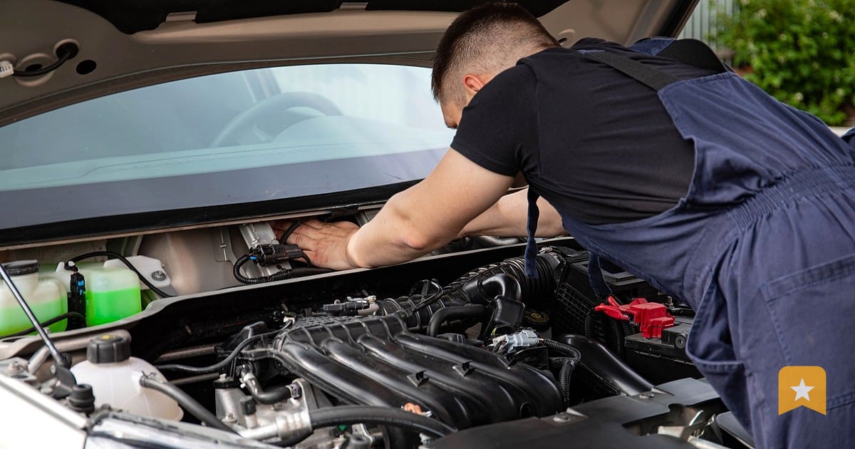 Mechanic leaning into an open car engine to diagnose or repair, the hands-on work that builds trust and earns customer reviews.