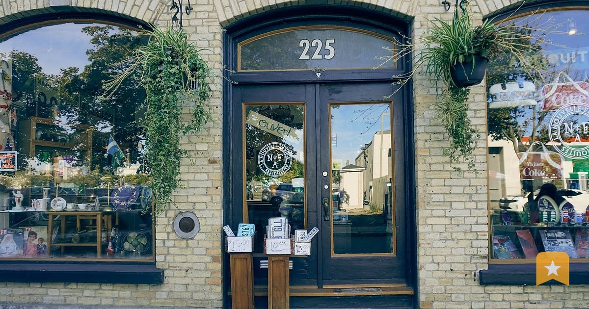Small storefront with blue door and number 225, ivy climbing the brick facade