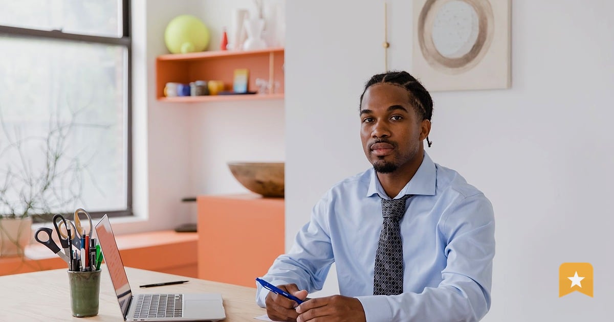 Business owner in light blue shirt writing on documents at desk, managing the administrative side of running a local business